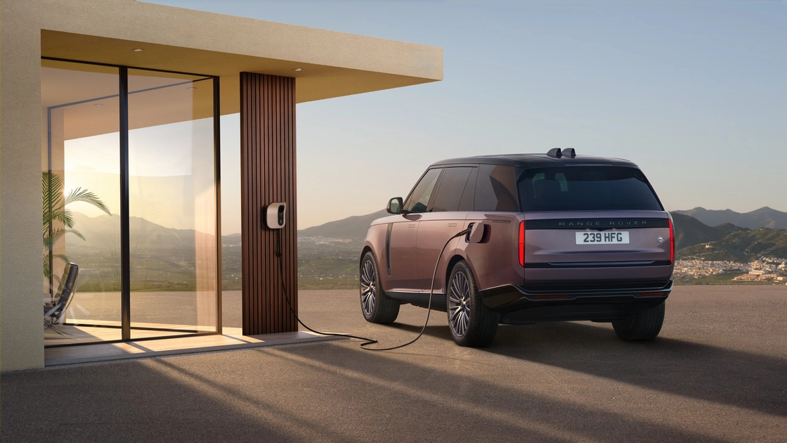 Range Rover заряджається біля сучасного будинку на заході сонця