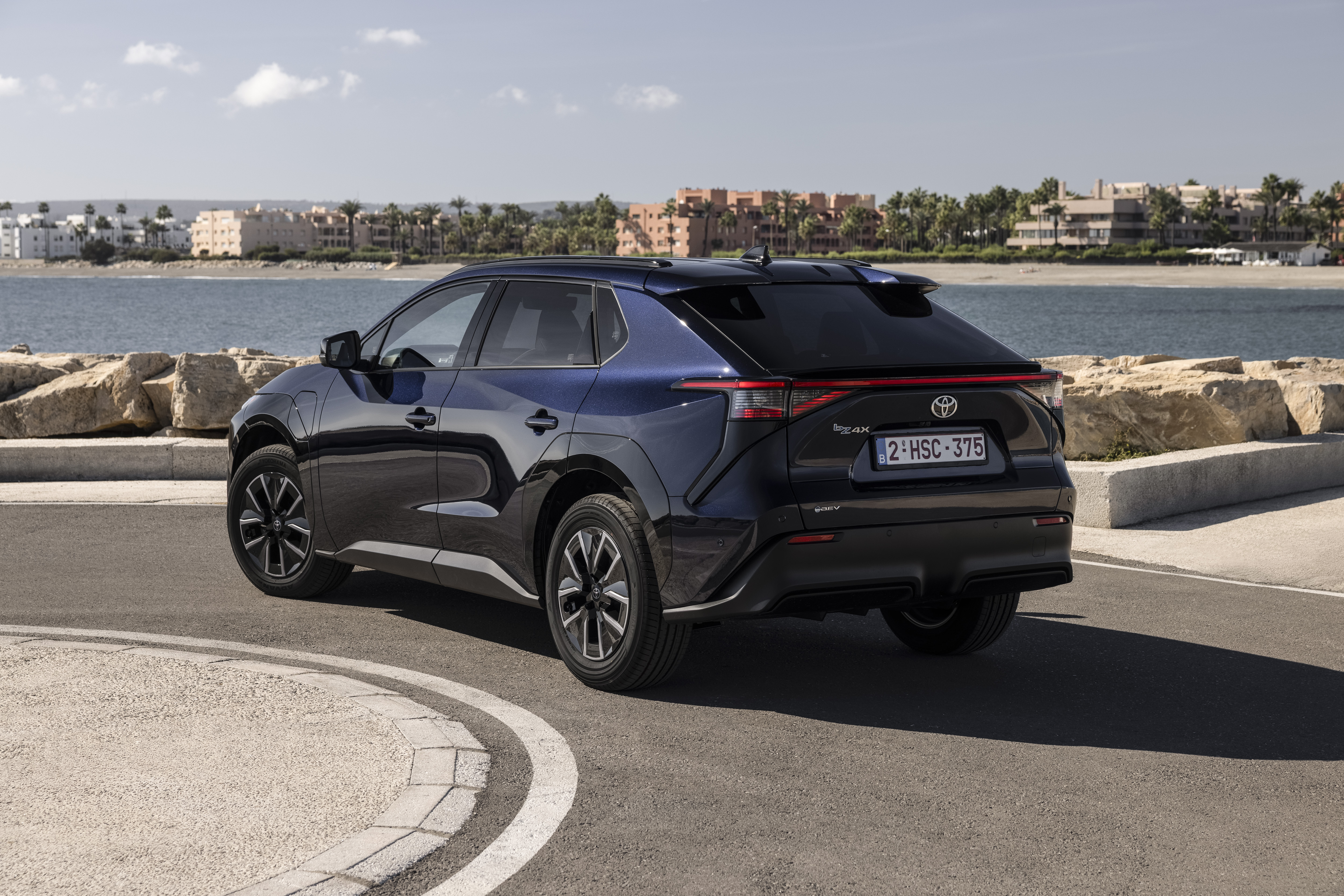 2026 Toyota bZ4X в движении, боковой вид на глубоком синем металлике